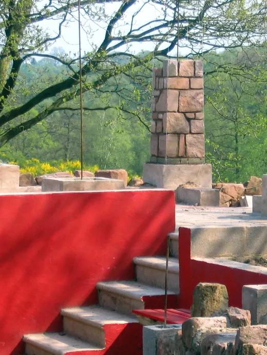 Stone steps leading to a terrace with partially built stone columns.