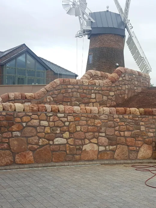 A stone wall with a windmill in the background.